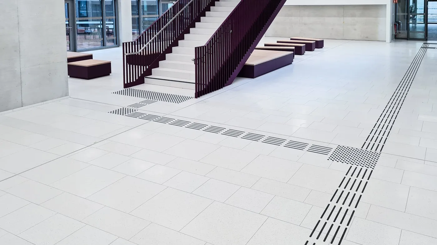 TAKTILo®_Core Bodenleitsystem in modernem Gebäude mit schwarzen taktilen Linien und Punkten.